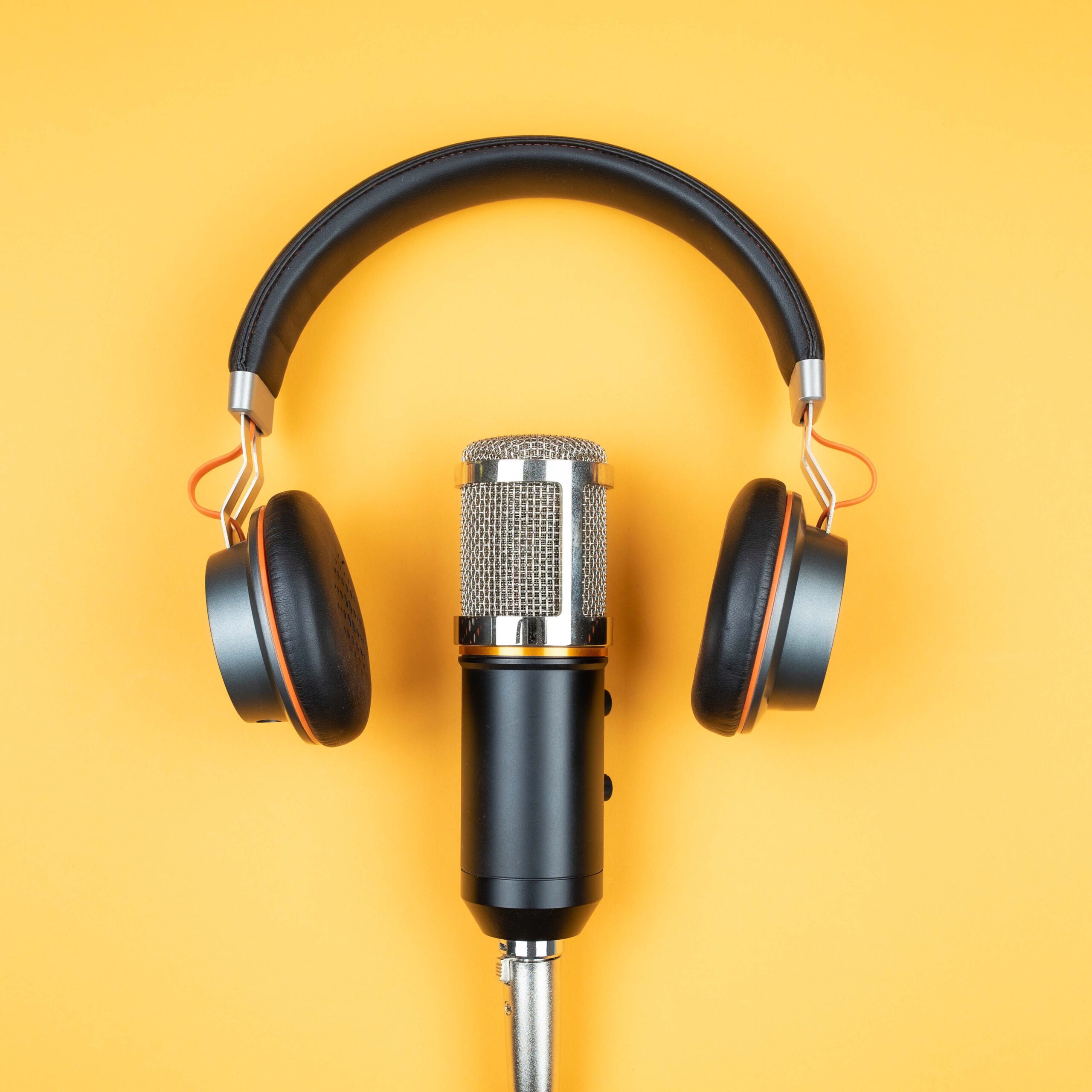 directly above view of headphones and recording microphone on orange background